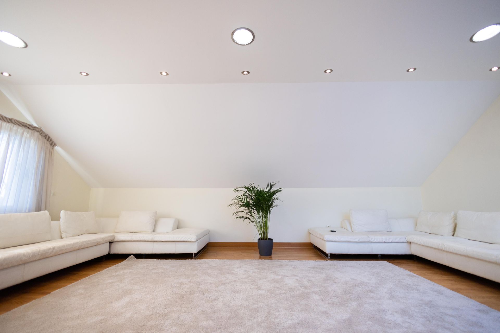 A spacious minimalist living room with white sofas and natural lighting.